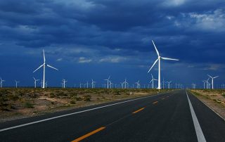 a picture of onshore wind farm next to highway