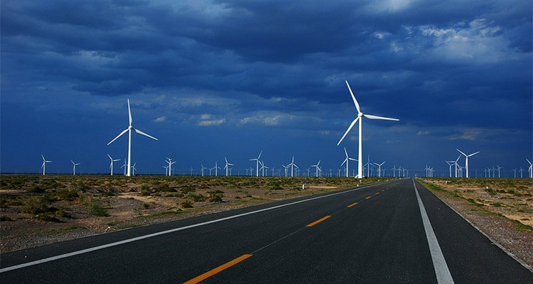 a picture of onshore wind farm next to highway